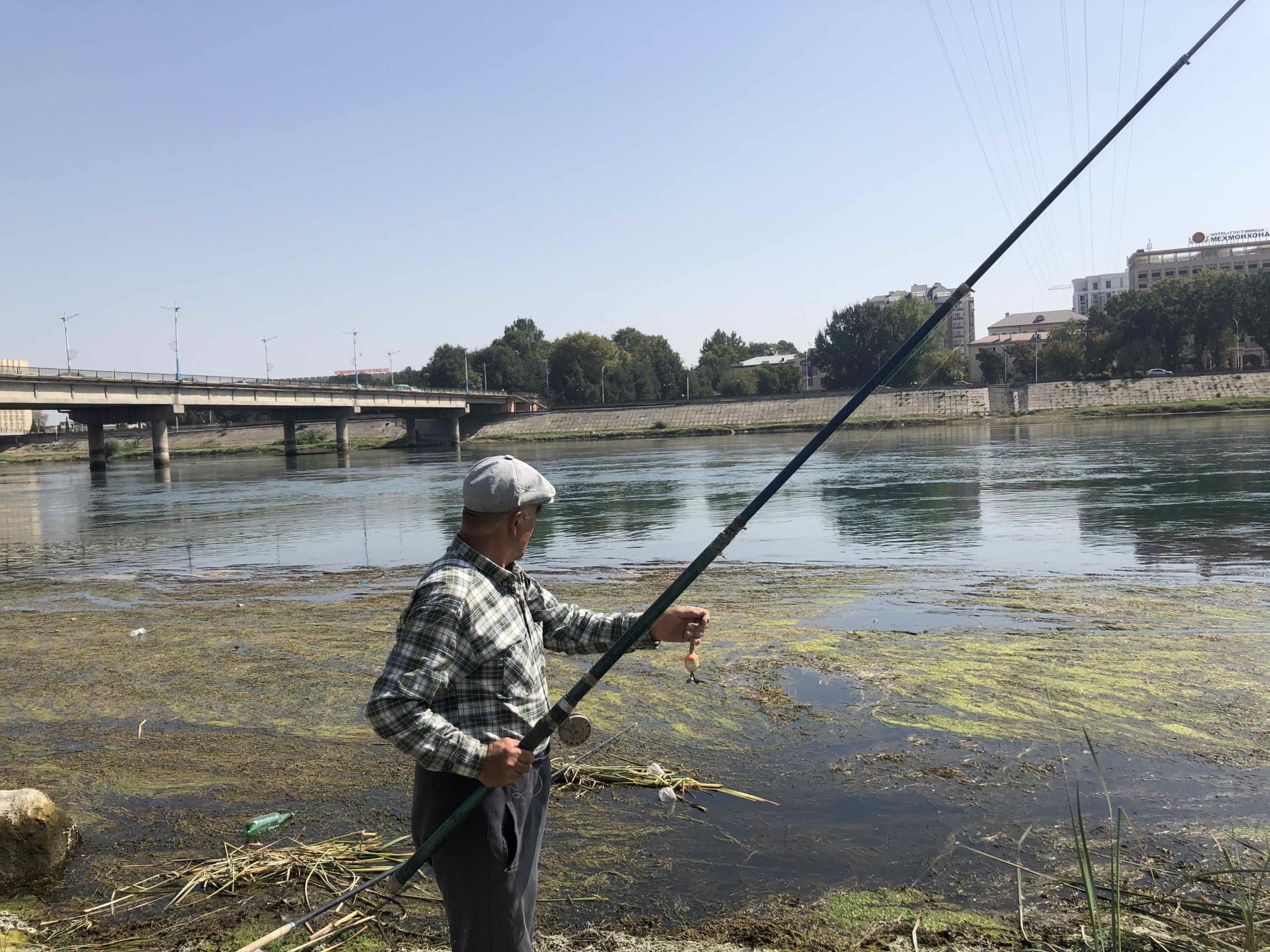 A photograph of a fisherman fishing on a river on Matt Spencer’s cycling for sturgeon journey.