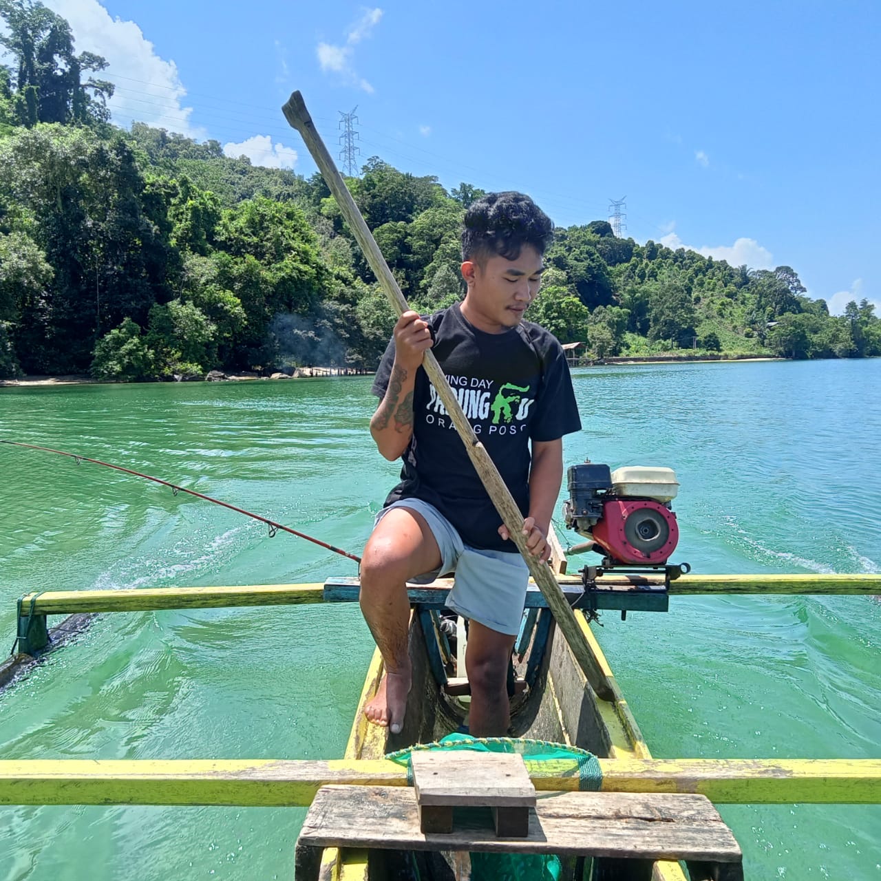 A photograph of a man who works with our partner PROGRES in Sulawesi, standing on the back of a boat in a lake.