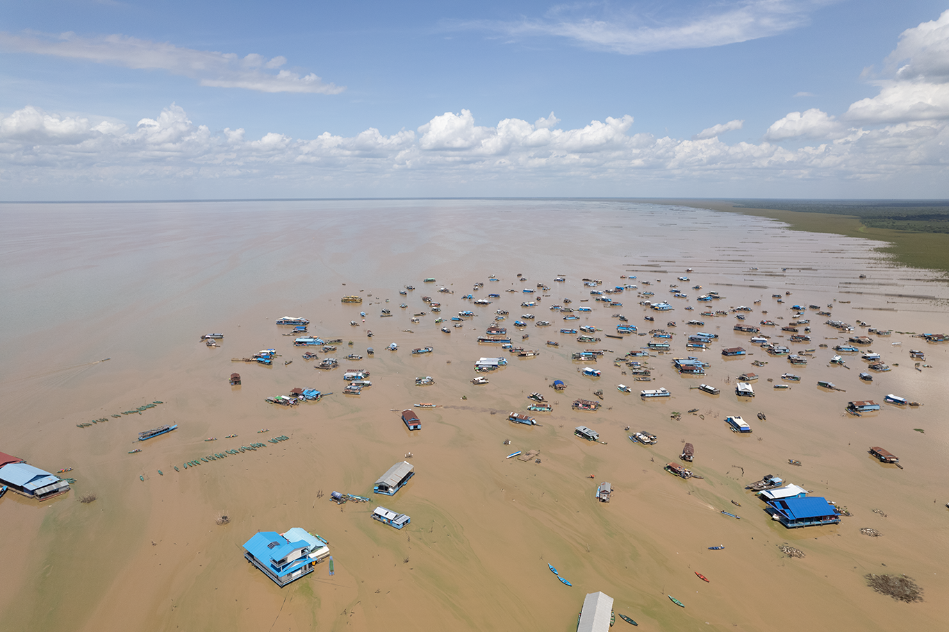 An aerial view of a lake with dozens of floating houses on it. Conservation southeast asia. Credit Ben Hayes