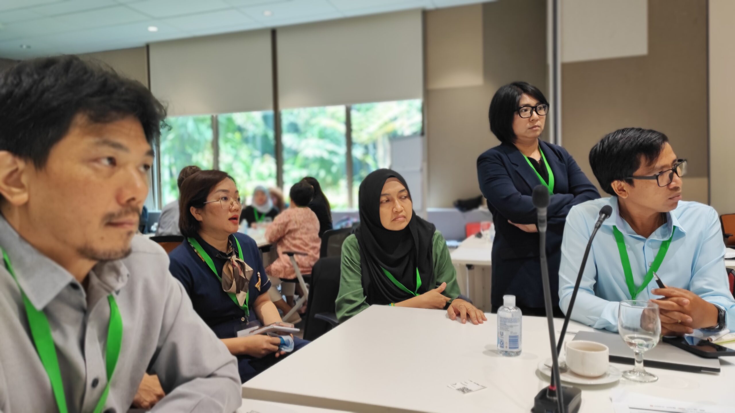 Four people sitting around a table looking forward, in a room with other people also paying attention in the background. Conservation southeast asia. Credit Mike Baltzer