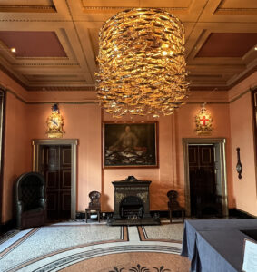A nice room with a big chandelier in the middle that looks like a massive shoal of fish swimming in a circle.