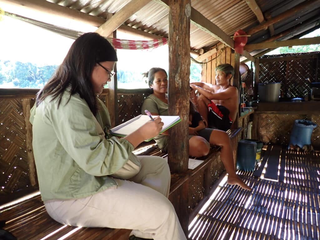 Two women sitting and talking, one has a notepad and pen.