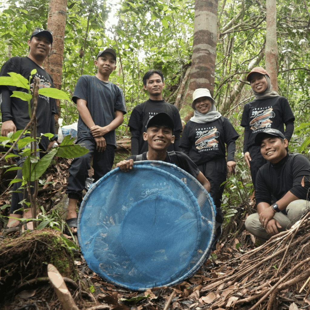 Seven of the team from SHOAL's partner the Tropical Conservation Society in the forest, smiling for the camera.